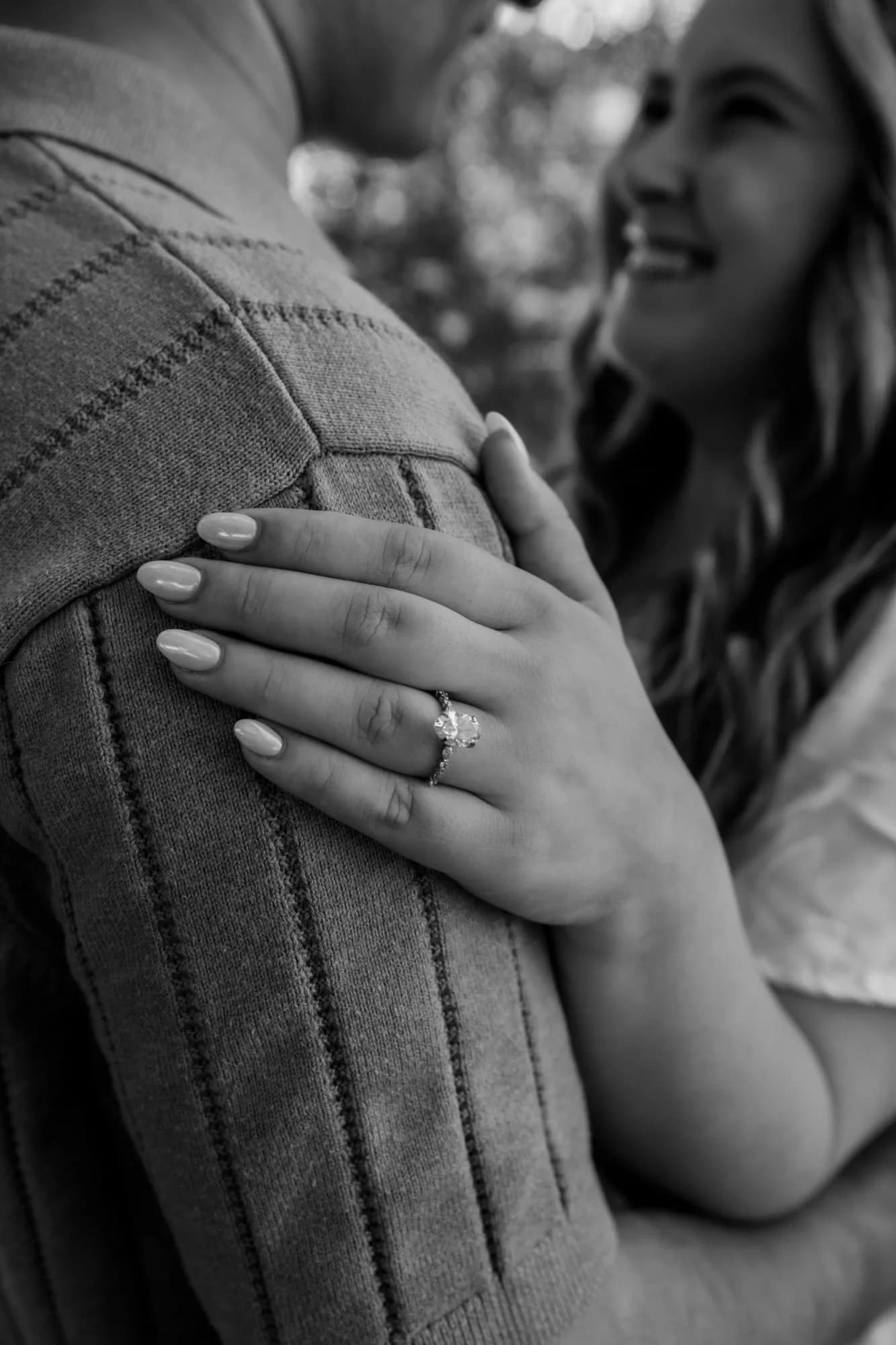 Ally’s hand, wearing the engagement ring, resting on Gavin’s shoulder