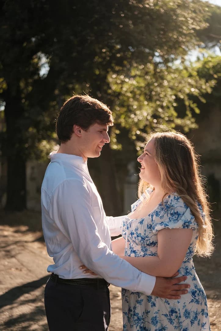 Gavin and Ally smiling at each other in the sun under the trees in Rome