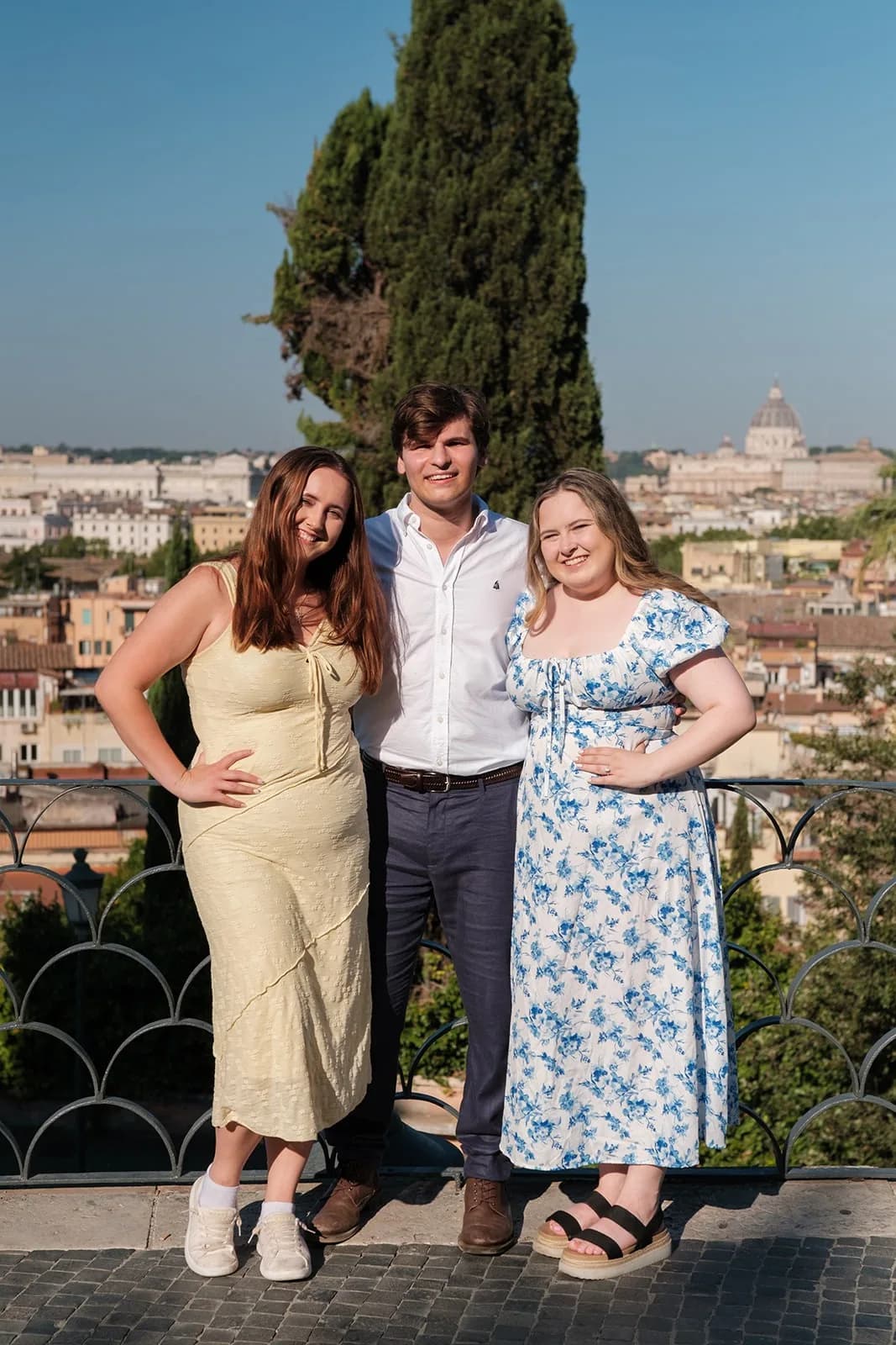 Gavin and Ally with a friend at a railing above the rooftops of Rome, with St. Peter’s dome behind them