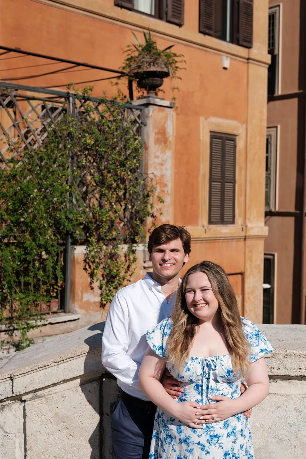 Gavin holding Ally from behind in front of an orange building in Rome